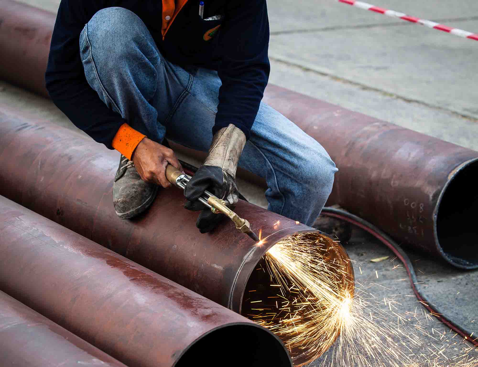 Operation scene of a portable cutting machine cutting a ductile iron pipe, with the machine performing a steady circular cut